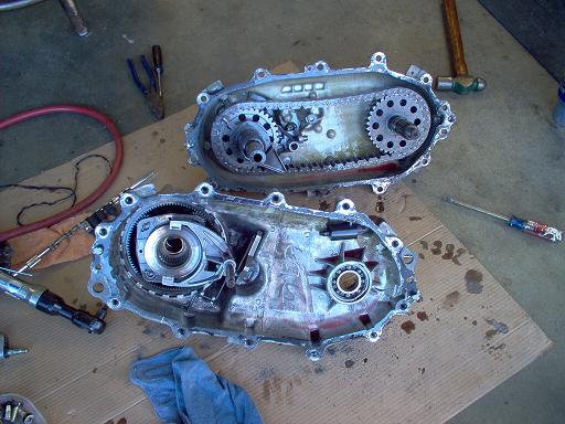 Chain-driven gearcase split into two halves on cardboard during a rebuild