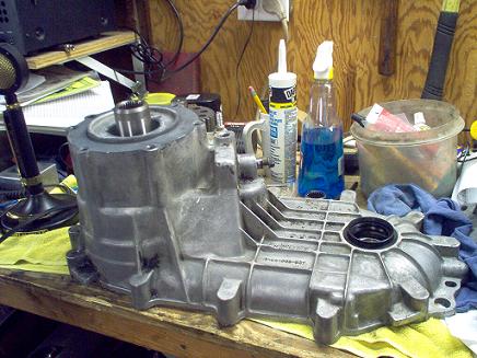 1988 Ford Bronco - A disassembled transfer case sits on a wooden workbench, surrounded by various repair and cleaning supplies.