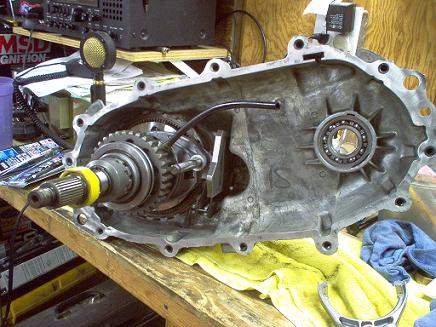 1988 Ford Bronco - A disassembled transfer case sits on a workbench, revealing its internal gears and bearings.