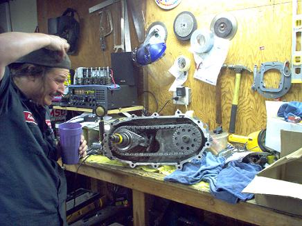 1988 Ford Bronco - Transfer case assembly sits on a workbench with a man observing it in a garage setting.