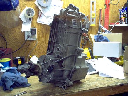 1988 Ford Bronco - Transfer case assembly resting on a workbench in a garage setting.