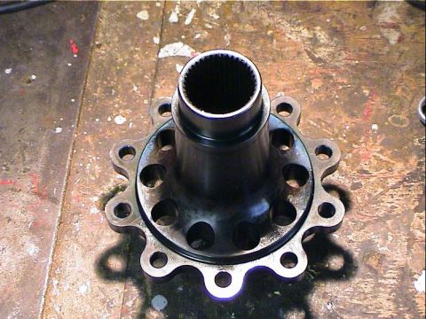 1979 Ford Bronco - A differential part with a splined interior and a flange 10 bolt holes is shown on a workbench.