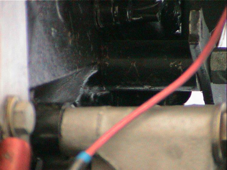 Close-up of engine bay with red wire and metal components