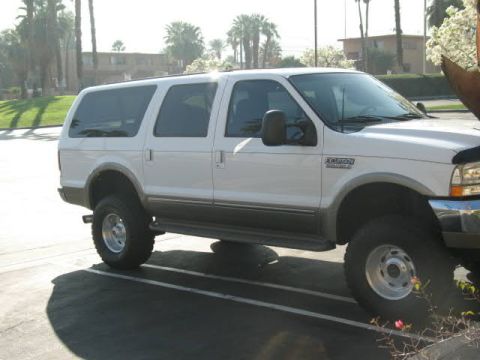 2002 Ford Excursion - A white Ford Excursion is parked in a lot with palm trees in the background.