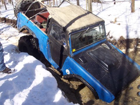 1974 Ford Bronco - This off-road vehicle appears to be stuck in a muddy and snowy terrain, with its tires deep in the muck.