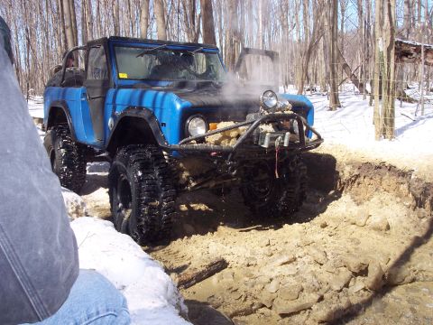1974 Ford Bronco - This modified SUV is navigating a muddy, wooded terrain in the snow.