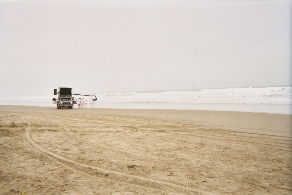distant vehicle towing equipment along a wide foggy beach by the surf