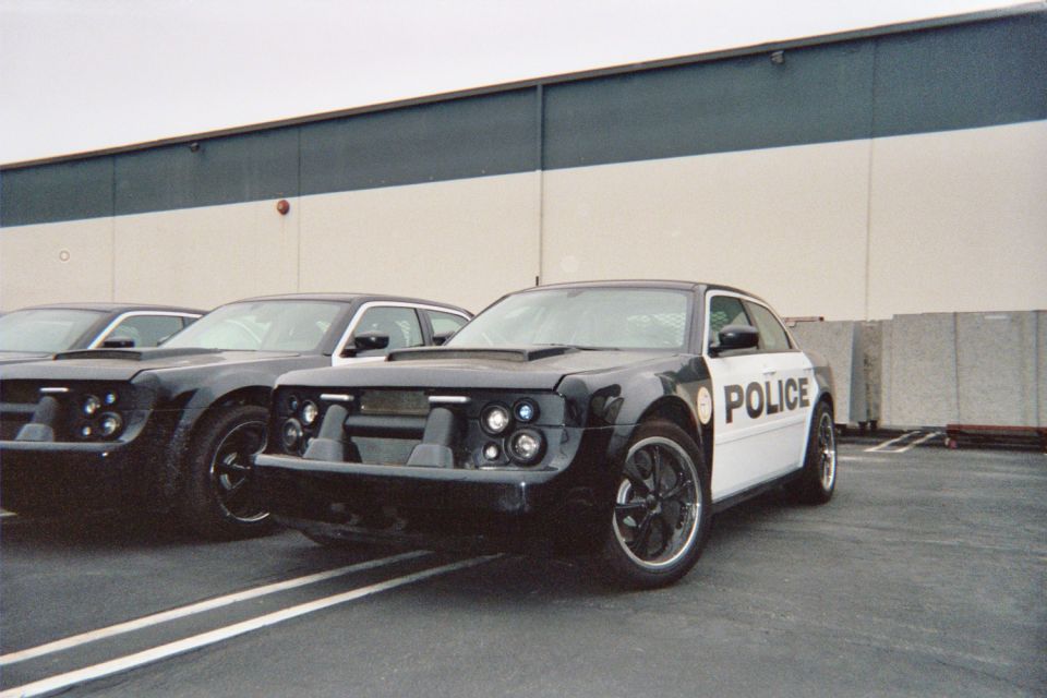 Black-and-white POLICE-liveried custom sedan parked beside another car