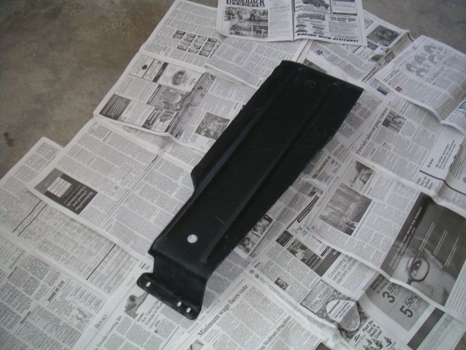 black plastic car part laid out on newspapers