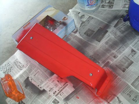 1994 Ford Bronco - Car door panel being painted red, laid out on newspapers with painting supplies.