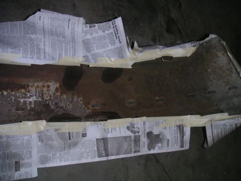1994 Ford Bronco - A rusted metal part is covered with newspaper and masking tape, likely for protection or preparation.