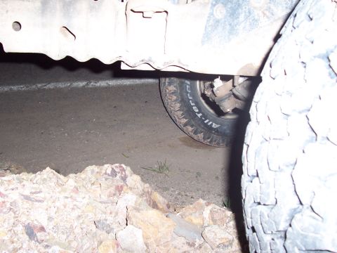 1996 Ford Bronco - Close-up view of a vehicle's chassis and tire, with rocks in the foreground.