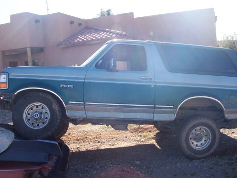 1996 Ford Bronco - Side profile of a teal and gray 1996 Ford Bronco with a lifted suspension.