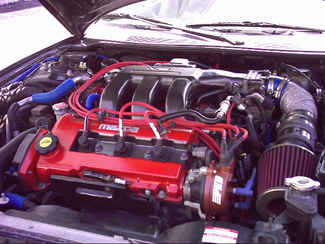 Engine bay with red Mazda valve cover, red plug wires, and cone air filter