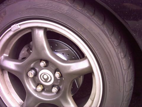 1997 Ford Probe - A close-up view of a vehicle's wheel and slotted brake rotor, with visible tire sidewall text.