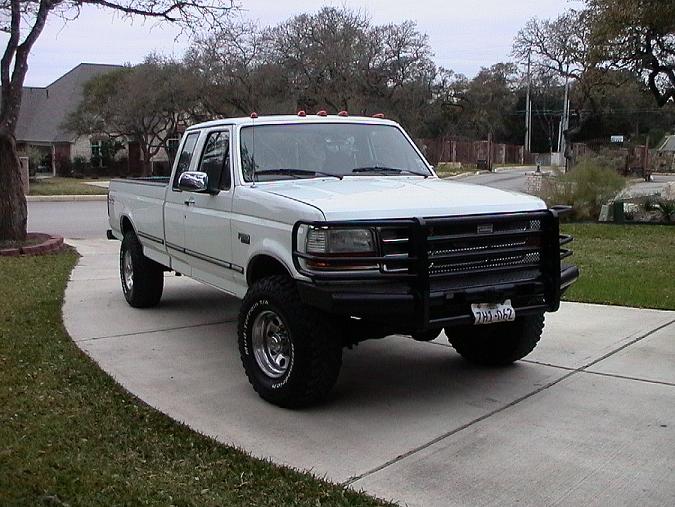 White Ford F-250 extended-cab 4x4 with black brush guard parked on a driveway, Texas plate