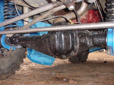 1969 Ford Bronco - Close-up view of a vehicle's differential housing and suspension components, partially covered by blue plastic.