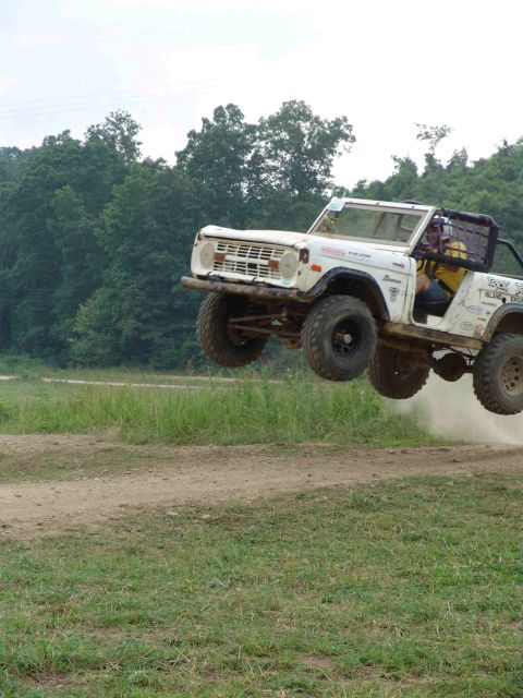 1972 Ford Bronco - A white 1972 Ford Bronco is captured mid-air during a jump over a dirt track.