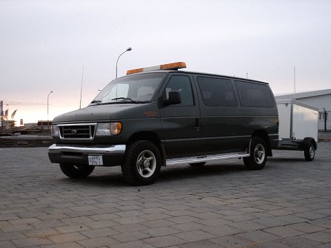 1996 Ford Bronco - Ford E-Series van, likely early 2000s model, equipped with a light bar and towing a trailer.