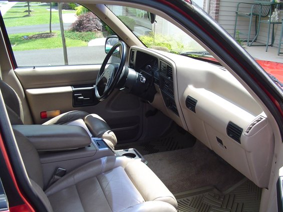 Tan leather interior of an SUV showing steering wheel, dash and front seats