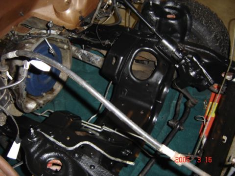 1990 Ford Bronco - Empty engine bay photographed from above with the freshly painted gloss-black inner fenders, frame rails and shock towers, brake booster an…