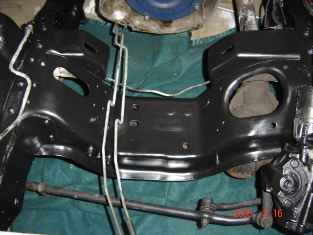 Freshly painted gloss black engine crossmember and frame in an empty engine bay