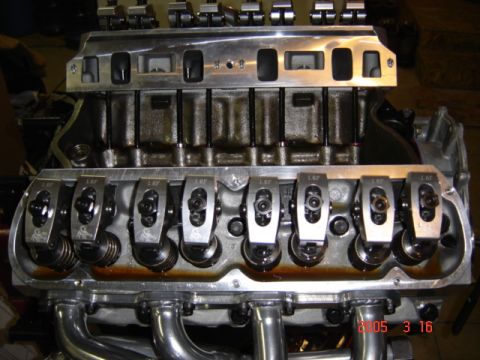 1990 Ford Bronco - Close-up along one bank of a V8 engine with the valve cover removed, showing eight polished roller rocker arms marked "1.6R" on an aluminum…
