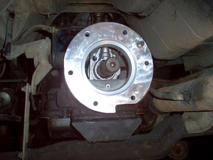 1988 Ford Bronco - Close-up view of a transfer case adapter plate installed on a vehicle's transmission.
