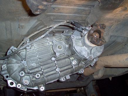 1988 Ford Bronco - Underside view of a vehicle's transfer case, showing the main housing and the yoke for the driveshaft connection.