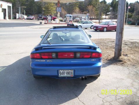 1997 Ford Probe - Rear view of a blue 1997 Ford Probe GT parked at a gas station. A red Probe is visible in the background.
