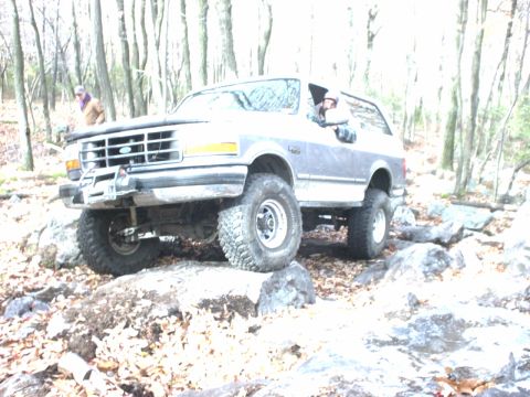 1995 Ford Bronco - This lifted Ford Bronco navigates a rocky trail through a forest.