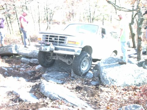 1995 Ford Bronco - A Ford Bronco is shown attempting to traverse a rocky obstacle on an off-road course.