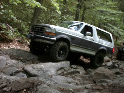 1995 Ford Bronco - This 1995 Ford Bronco navigates a challenging rocky terrain in a forest setting.