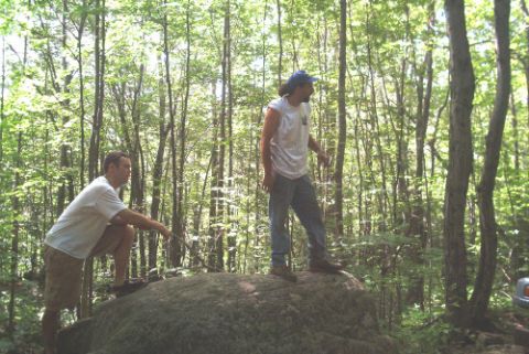 1995 Ford Bronco - Two men are in a wooded area, one standing on a rock and the other kneeling.