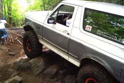 1995 Ford Bronco - A modified Ford Bronco navigates a rocky trail with its driver behind the wheel.