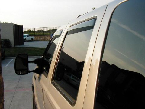 2002 Ford Excursion - A white 2002 Ford Excursion is parked next to a building, with another white truck visible in the background.