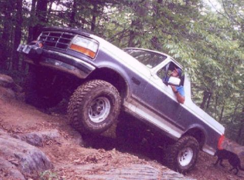1995 Ford Bronco - This truck is navigating a rocky incline on a wooded trail.
