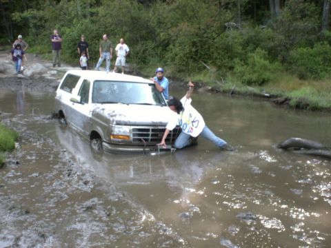 1995 Ford Bronco - A group of people watch as a 1995 Ford Bronco gets stuck in a muddy stream.