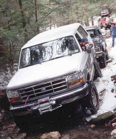1995 Ford Bronco - A convoy of Ford Broncos navigates a snowy, wooded trail.