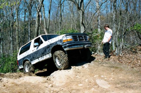 1995 Ford Bronco - A man watches a two-tone Ford Bronco navigate a challenging off-road trail.