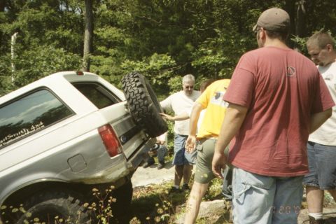 1995 Ford Bronco - A group of men observe a Ford Bronco navigating a challenging off-road terrain.