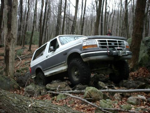 1995 Ford Bronco - Ford Bronco navigates a rocky trail through a dense forest.