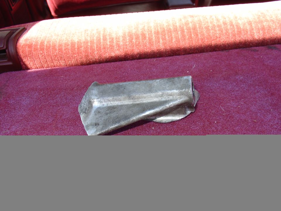 Bent metal bracket resting on burgundy car seat fabric