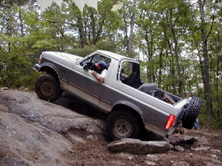 1995 Ford Bronco - This silver Ford Bronco is navigating a rocky trail, with its driver's side and rear spare tire clearly visible.