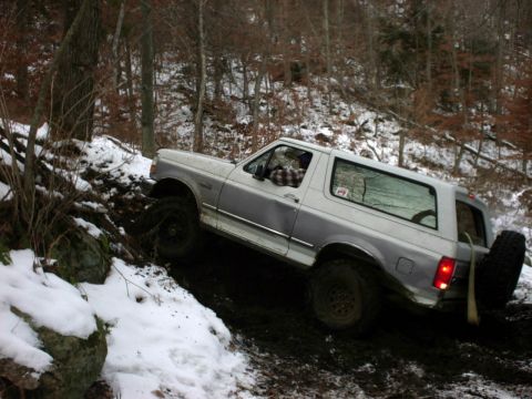 1995 Ford Bronco - Ford Bronco navigates a challenging off-road course covered in mud and snow.