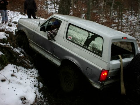 1995 Ford Bronco - A Ford Bronco navigates a challenging off-road course with snow and mud on the ground.