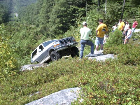 1995 Ford Bronco - This 1995 Ford Bronco is navigating a challenging off-road course with spectators observing the action.