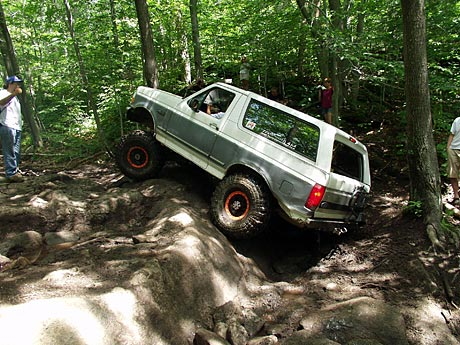 1995 Ford Bronco - This 1995 Ford Bronco is navigating a challenging off-road course in a wooded area.
