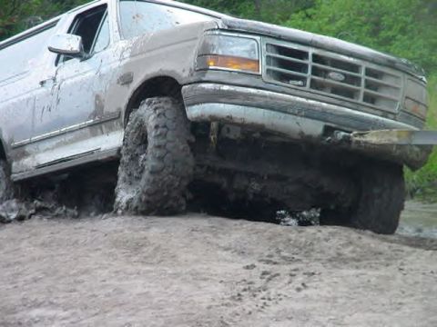 1995 Ford Bronco - This SUV is deeply embedded in thick mud, with its front tire submerged.