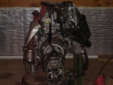 1992 Ford Bronco - Engine and transmission assembly on a stand, showing complex wiring and exhaust components.
